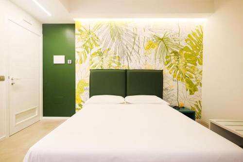 um quarto com uma cama branca e um papel de parede tropical em Casa dei Venti - Guest House em Terracina