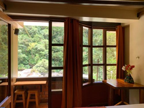 Cette chambre dispose d'une grande fenêtre, d'une table et de chaises. dans l'établissement Panorama B&B, à Machu Picchu