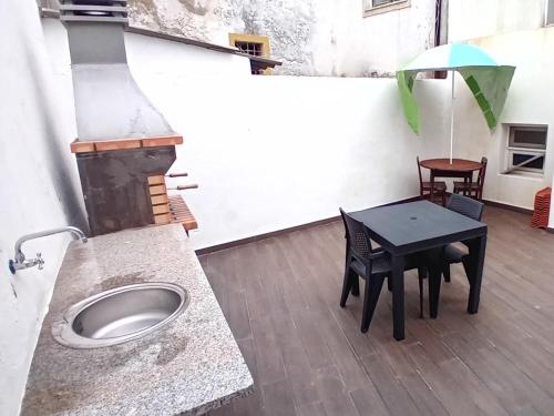 a patio with a table and a grill with an umbrella at Apartment in Semeador in Portalegre