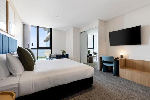 um quarto de hotel com uma cama e uma televisão de ecrã plano em Quest Woolooware Bay em Cronulla