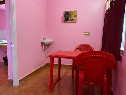 een rode tafel en stoelen in een badkamer met roze muren bij Valley Villa 2BHK in Kodaikānāl