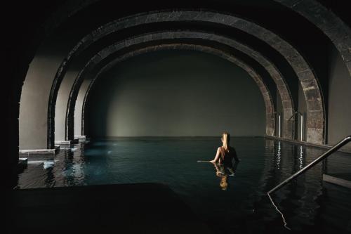 una mujer sentada en el agua en un túnel en NINE DOTS Azorean Art Boutique Hotel, en Ponta Delgada