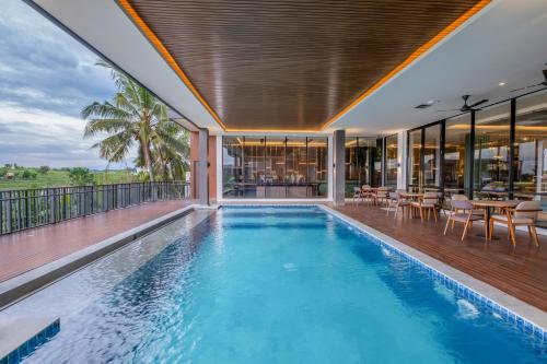 uma piscina interior com mesas e cadeiras numa varanda em ValStar Hotel Canggu em Canggu