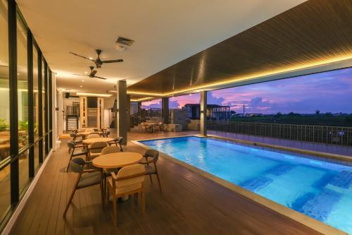 uma piscina no telhado de um edifício com mesas e cadeiras em ValStar Hotel Canggu em Canggu