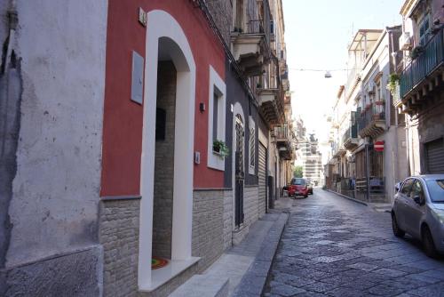 un callejón con un edificio rojo y blanco en una calle en HAPPY HISTORIC HOUSE, en Catania