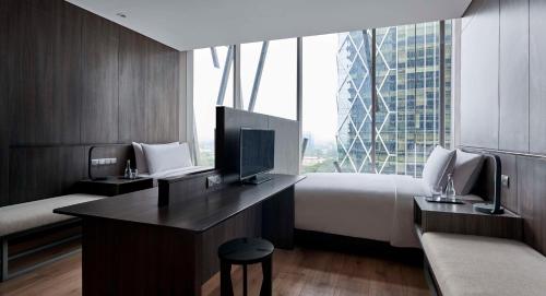 ein Hotelzimmer mit einem Bett und einem Schreibtisch mit einem TV in der Unterkunft Alila SCBD Jakarta in Jakarta