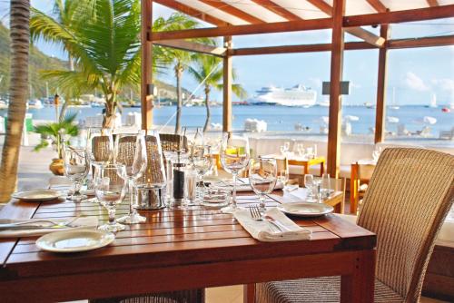 un tavolo in legno con bicchieri da vino e vista sull'oceano di Holland House Beach Hotel a Philipsburg