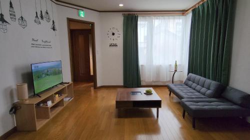 sala de estar con sofá y TV en SecondHouse Otaru Garden, en Otaru