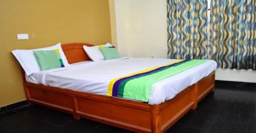 a bedroom with a bed with white sheets and green pillows at RAHUL STONE PALACE in Kodaikānāl