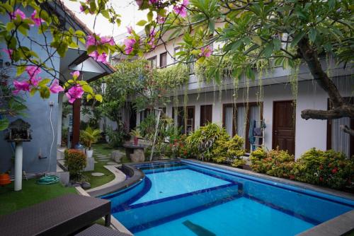 una piscina en el patio de una casa con flores en Bali Full Moon Guest House, en Canggu