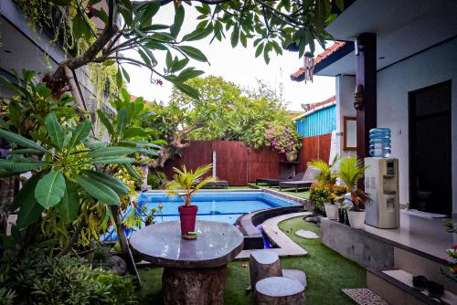 un patio trasero con una piscina con una mesa y una sidra de mesa en Bali Full Moon Guest House, en Canggu