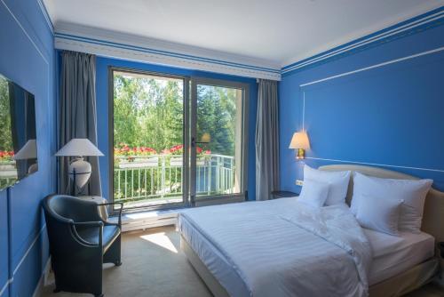 ein blaues Schlafzimmer mit einem Bett und einem Fenster in der Unterkunft Hotel Parc Belair in Luxemburg (Stadt)