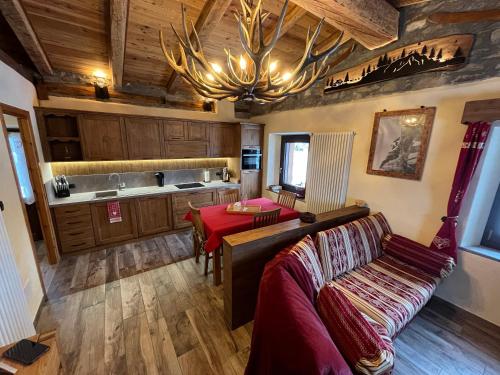 a kitchen with a couch and a table and a chandelier at Chalet Chez Louis - Alpine Charm with Mont Blanc View & Ski Access in Courmayeur