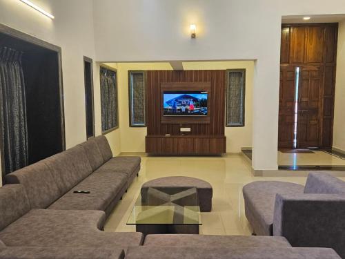 een woonkamer met een bank en een tv bij Seven Villa with Swimming pool in Panchgani