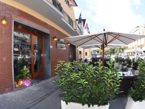 a patio with an umbrella and plants in front of a store at Albergo La Perla in Orbetello