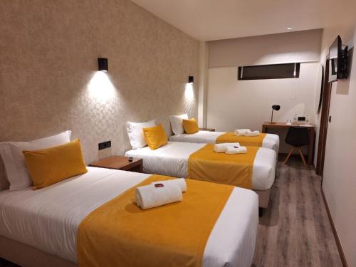 a hotel room with two beds with yellow sheets at 3M Hostel & Suites in Alvaiázere