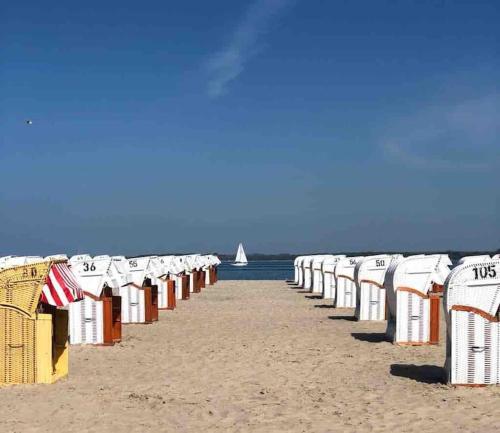 una fila de sillas de playa en una playa de arena en ٤Sweet Spot٤Geräumig-King Bed-Disney+-Parken, en Scharbeutz