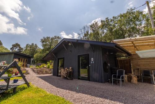 un hangar noir avec une table et des chaises devant lui dans l'établissement Mount Hillary Holiday Pods, à Cork