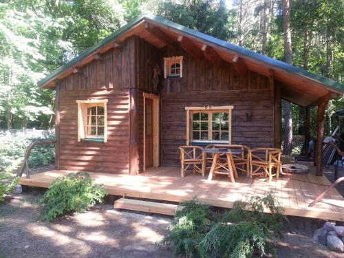 een blokhut met een tafel en stoelen op een terras bij Holzhaus Waldwichtel am Wald und See in Neuruppin