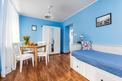 - une chambre bleue avec un lit, une table et des chaises dans l'établissement Oliwia, à Jastrzębia Góra