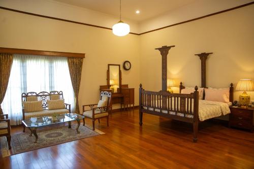 1 dormitorio con cama, sofá y mesa en Marlihill Bungalow - a CGH Earth SAHA Experience, en Ooty