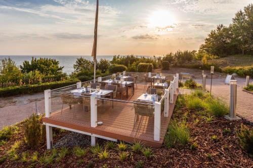 un restaurant sur une terrasse avec l'océan en arrière-plan dans l'établissement Hotel Bernstein, à Sellin