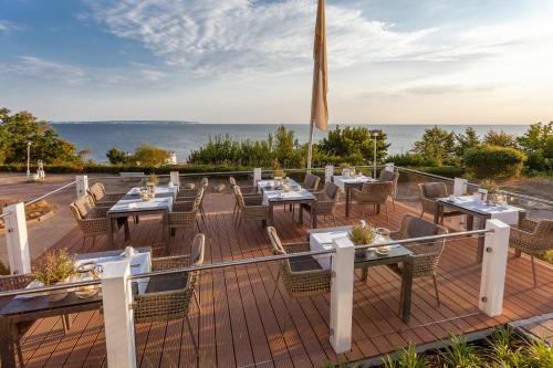 un patio avec des tables et des chaises et l'océan en arrière-plan. dans l'établissement Hotel Bernstein, à Sellin