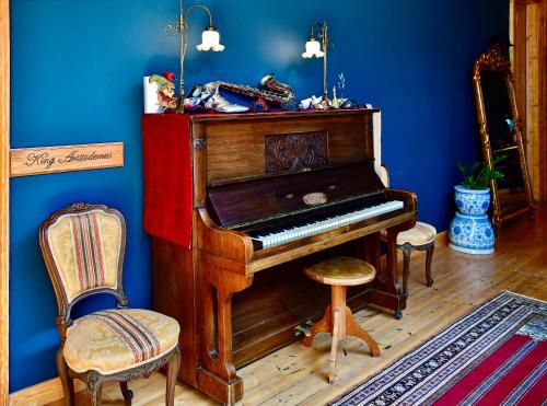 um piano de madeira num quarto azul com 2 cadeiras em VASILIKON Hotel 1888 the past is present HISTORICAL PRESERVATION MONUMENT em Kalamata