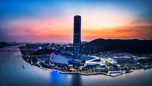 un grand bâtiment au milieu de l'eau au coucher du soleil dans l'établissement The St. Regis Zhuhai, à Zhuhai