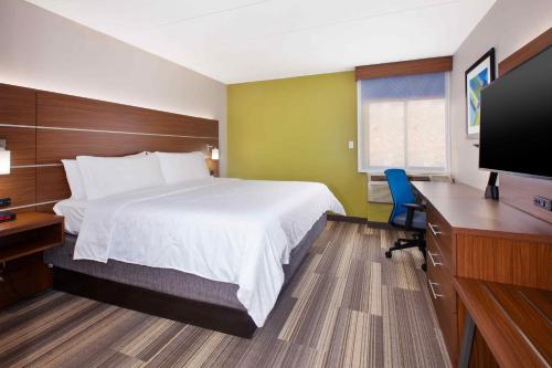 フェアファックスにあるHoliday Inn Express Fairfax-Arlington Boulevard, an IHG Hotelのベッド、デスク、テレビが備わるホテルルームです。