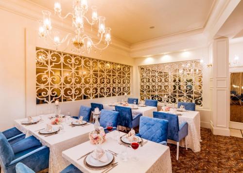 un restaurant avec des tables blanches, des chaises bleues et un lustre dans l'établissement Vuni Palace Hotel & Casino & SPA, à Kyrenia