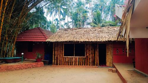 a small house with a thatch roof and a window at Ayurguru Ayurvedic Kalari Resort in Sultan Bathery