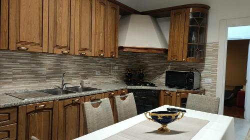 a kitchen with wooden cabinets and a sink and a table at Rome Apartment D'Amata in Ciampino