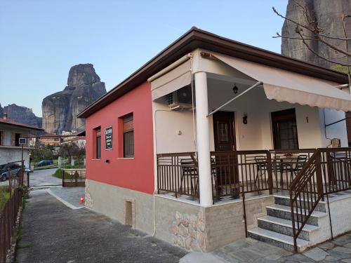 een roze gebouw met een balkon met tafels bij SOCRATES Ethnic and traditional Home in Kalabaka