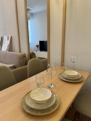 - une table en bois avec 2 assiettes et des verres à vin dans l'établissement Nomad Stay Apartments, à Durrës