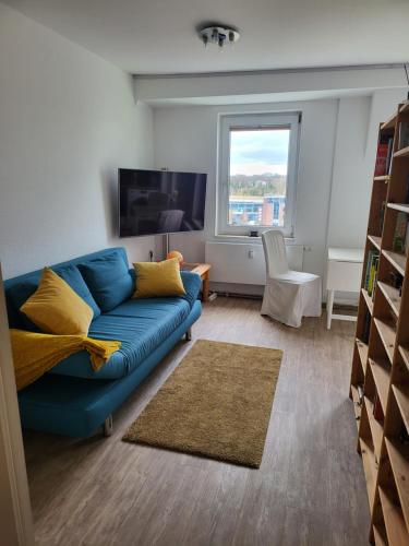 sala de estar con sofá azul y ventana en Ferienwohnung im Dachgeschoss mit Aufzug, en Rostock