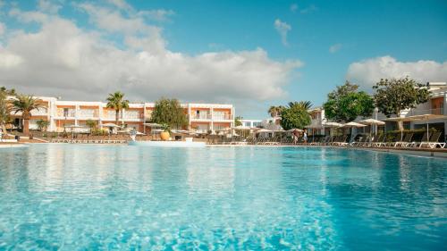 a swimming pool at a resort with chairs and umbrellas at Labranda Bahía de Lobos in Corralejo