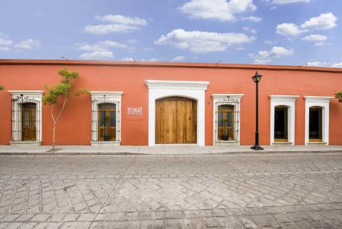 ein orangefarbenes Gebäude mit einer Holztür auf einer Straße in der Unterkunft XTILU Hotel - Adults only - in Oaxaca de Juárez