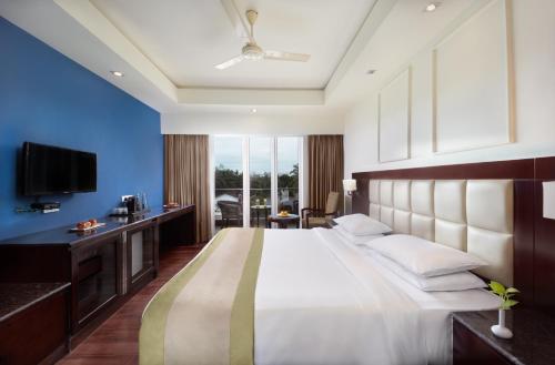 um quarto com uma cama grande e uma televisão em The Acacia Hotel & Spa em Candolim