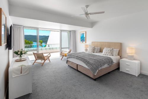 ein weißes Schlafzimmer mit einem Bett und einem großen Fenster in der Unterkunft Bella Vista East 4 Oceanview, Golf Buggy, Valet Service & Shared Pool in Hamilton Island