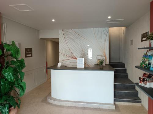 a white counter in a room with stairs at Hôtel-restaurant Les Colonnades in Saint-Fulgent