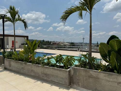 a resort with a pool and palm trees and a building at Lujoso apartamento central, nuevo y cómodo in Pereira