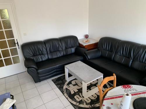 uma sala de estar com um sofá preto e uma mesa em Chaleureux logement familial jusqu'à 6 personnes em Annemasse