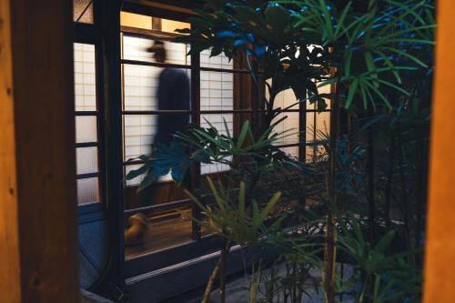 una persona que atraviesa una puerta con plantas en Johns House じょんのやど, en Himeji