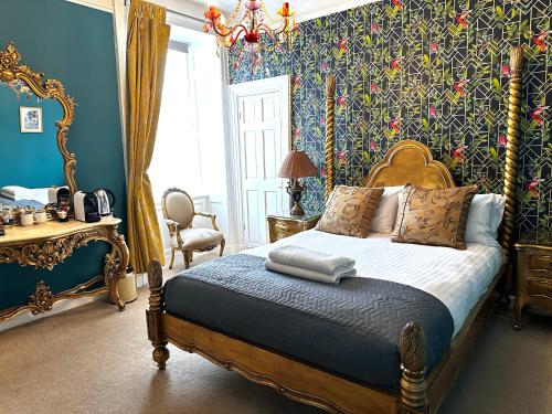 una camera da letto con un letto con pareti blu e carta da parati floreale di The Golden Fleece Inn a Porthmadog