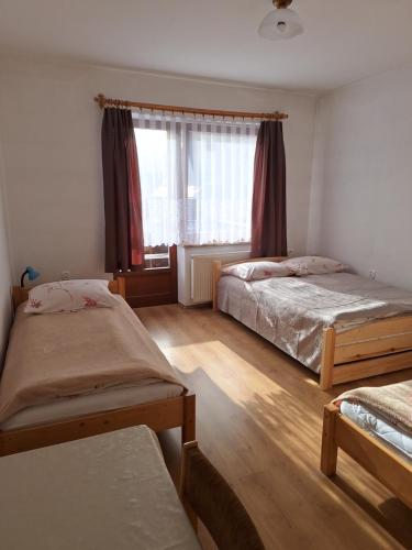 a bedroom with two beds and a window at WynajemPokoi-StołówkaGerlachscŁętowskiWłŁętowskaM ŁętowskaL Łętowska-HyłaB in Białka Tatrzanska