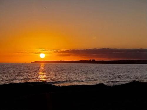 a sunset over a body of water with the sun setting at MAREA Algarve - Sea view sunny apartment in Alvor in Alvor