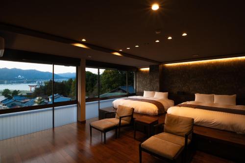 een slaapkamer met 2 bedden en een groot raam bij Kikunoya in Miyajima