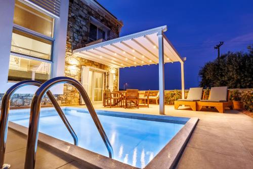 einen Pool mit einer Pergola neben einem Haus in der Unterkunft Petritis Villas in Nea Iraklitsa