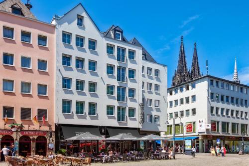 um grupo de edifícios numa rua com mesas e cadeiras em CityClass Hotel Alter Markt em Colónia